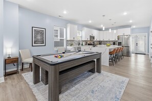 A modern kitchen with white cabinets, a pool table, and a bar area. - Family 4BR Retreat with Games and Fun for ALL (Indianapolis)