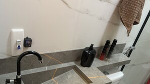 Ein Badezimmer mit Marmorwaschbecken, Toilette und Duschbereich.