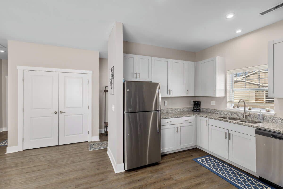 A modern kitchen with white cabinets, a stainless steel refrigerator, and a granite countertop.