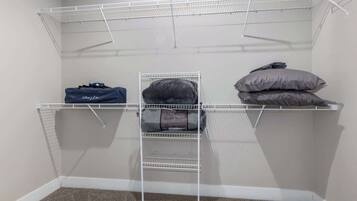 Ein begehbarer Kleiderschrank mit Metallregalen, einer Kleiderstange und einer Aufbewahrungstasche.