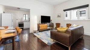 Un soggiorno moderno con un divano, una televisione e un'area pranzo con tavolo e sedie.