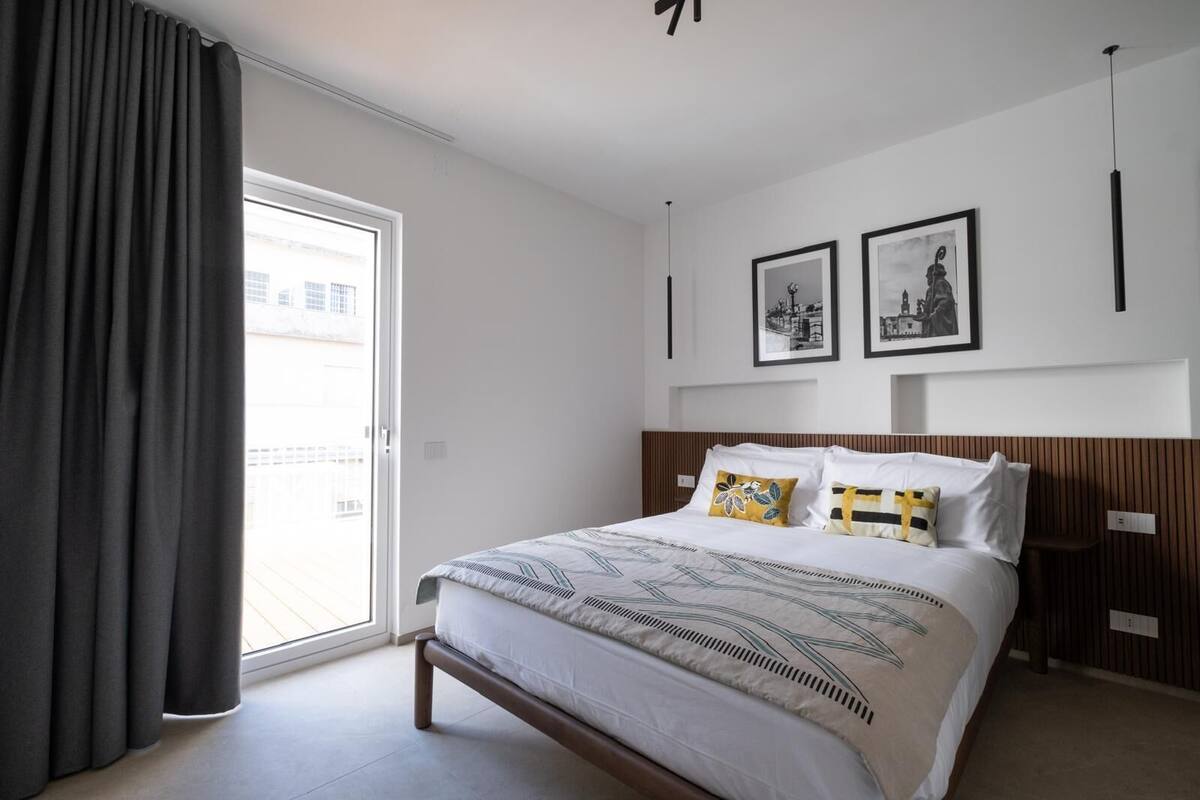 Une chambre d’hôtel moderne avec un grand lit, une tête de lit en bois et deux tableaux encadrés au mur.
