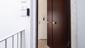 Een hal met een dubbele deur, een lichtschakelaar aan de muur en een afstandsbediening.