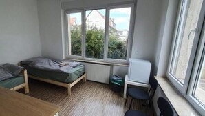 A dormitory room with a single bed, a small desk, a chair, and a radiator. - Hotel Grünewald chs (Hannover)