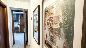 A hallway with a door leading to a kitchen area. There are framed pictures on the wall. - Camaiore - Cozy Home Between Alps and Sea for Families and Groups (Camaiore)