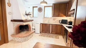A kitchen with a stone fireplace, wooden cabinets, a countertop with appliances, and a tiled floor. - Camaiore - Cozy Home Between Alps and Sea for Families and Groups (Camaiore)