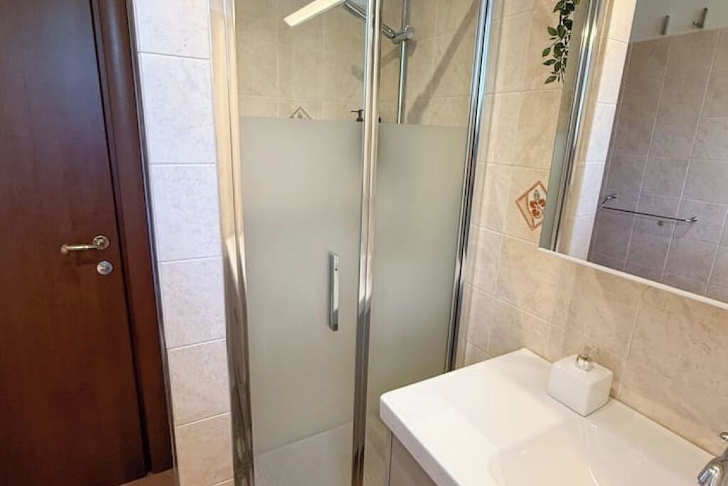 Une salle de bain avec une douche à parois de verre, un lavabo blanc et un miroir.