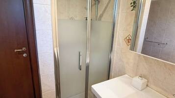 Une salle de bain avec une douche à parois de verre, un lavabo blanc et un miroir.