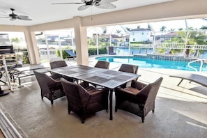 Un espace extérieur abrité comprenant une piscine, une table à manger et des chaises.