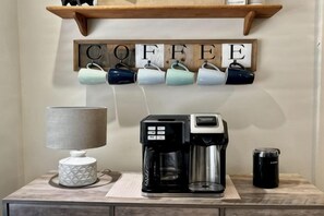 Un coin café avec une machine à café, des tasses et une cafetière, le tout installé sur une table.