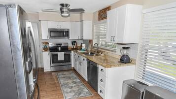 A kitchen with white cabinets, stainless steel appliances, a microwave, oven, and a blender.