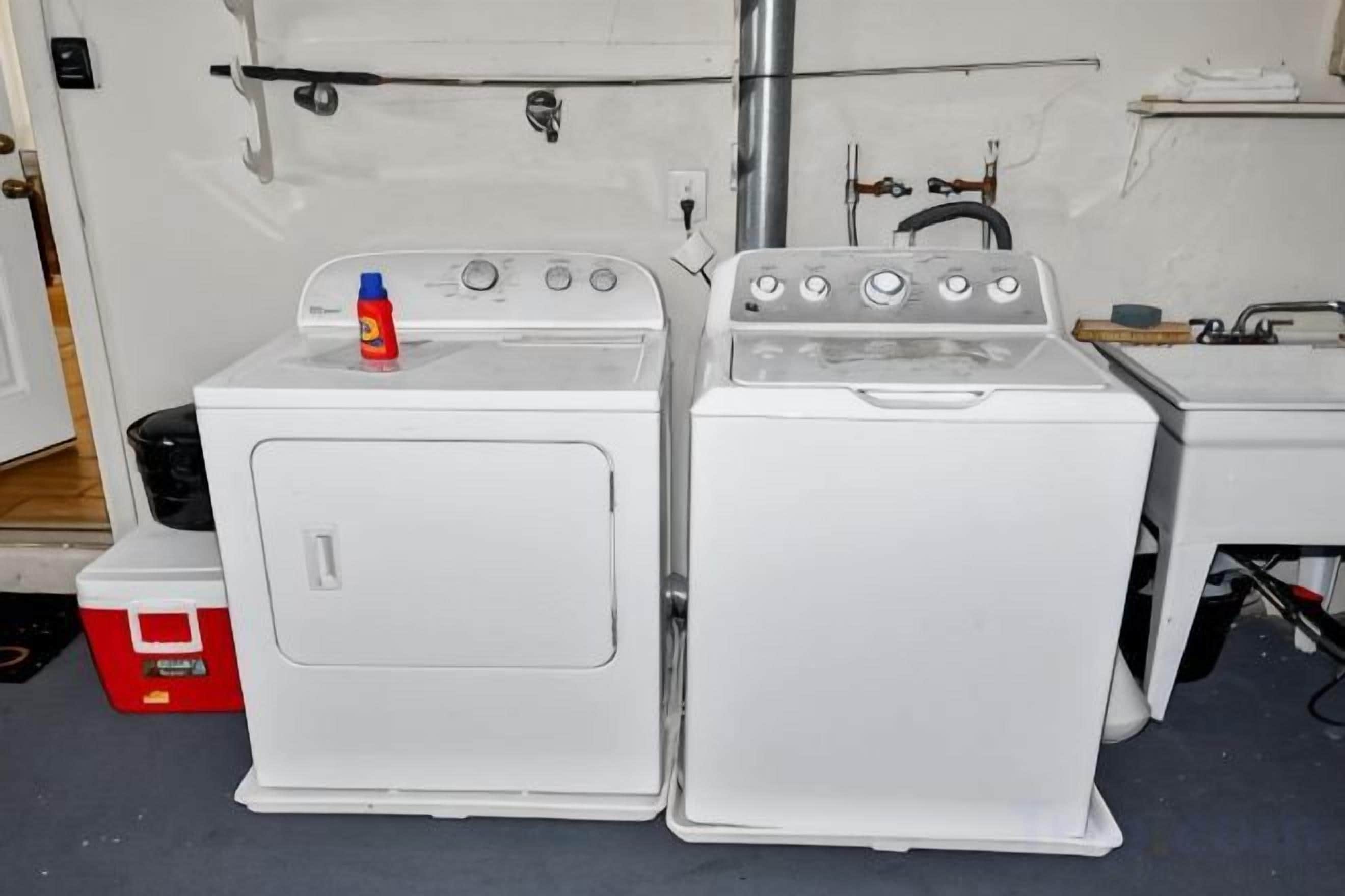 A laundry area with two white washing machines and a red cooler.