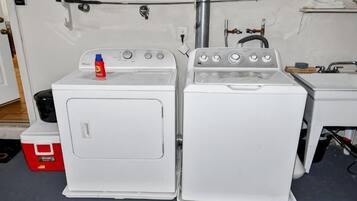 A laundry area with two white washing machines and a red cooler.