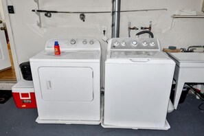 Un espace buanderie avec deux machines à laver blanches et une glacière rouge.