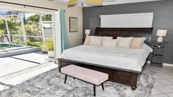 A bedroom with a large bed, a ceiling fan, a nightstand, and a view of a pool through a sliding door.