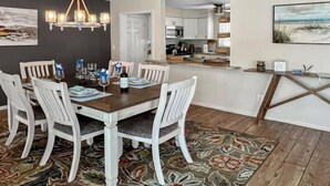 A dining area with a wooden table, white chairs, a chandelier, and a patterned rug. - Coral Sunshine - large south terrace with pool/spa (Cape Coral)