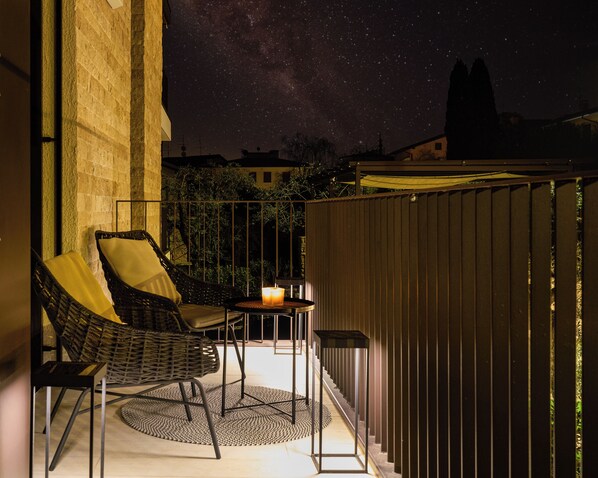 A balcony with two wicker chairs, a small table with a candle, and a view of the night sky. - SalvatoreHomes - Torri del Benaco (Torri del Benaco)