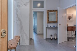 A modern interior with a marble wall, a wooden bench, a mirror, and a bar area. - Alta Marea Apulia sea view (Bari)