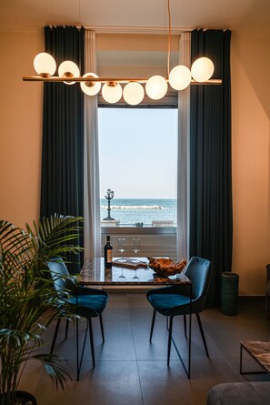 A dining area with a view of the sea, featuring a table with chairs, a bottle of wine, and a glass. - Alta Marea Apulia—Sea View   (Bari)