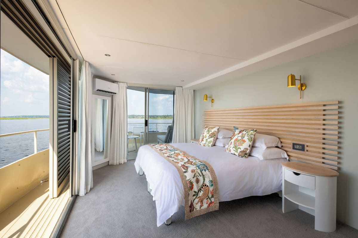 A modern hotel room with a large bed, a bedside table, and a view of the sea.