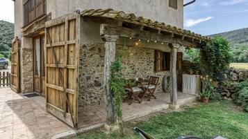 Un edificio in pietra rustica con un balcone in legno, posti a sedere all'aperto e un'area giardino.