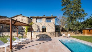 Un bâtiment en pierre doté d’une piscine, d’un espace extérieur aménagé et d’une pergola.