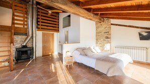 Une chambre à coucher avec un lit, un plafond en bois, un mur en pierre et une cheminée.