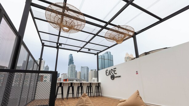 Un bar situé sur le toit, offrant une vue panoramique sur la ville, avec un comptoir et un espace salon agrémenté de coussins.