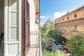 Vista desde un balcón sobre una calle con coches estacionados y edificios.