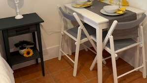 En matplats med ett bord dukat för två personer, ett litet sidobord med en lampa och en stol med en kudde.