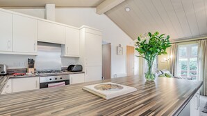 Una cocina moderna con armarios blancos, una encimera de madera, una estufa a gas y un florero con flores.