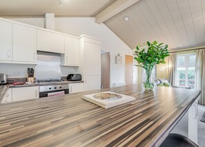 A modern kitchen with white cabinets, a wooden countertop, a gas stove, and a vase with flowers. - 2 bedroom accommodation in Bala, (Bala,)