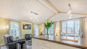 Una sala de estar moderna con un sofá, un televisor, una chimenea y un comedor con una mesa dispuesta para cuatro.