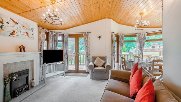 Una sala de estar acogedora con chimenea, televisor, sofá con cojines rojos y un comedor con mesa y sillas.