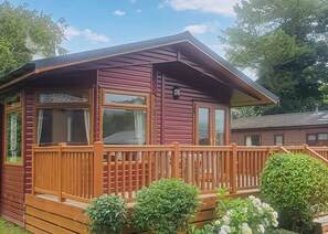 A cabin with a wooden deck, large windows, and a number '54' on the side. - 2 bedroom accommodation in Bala, (Bala,)