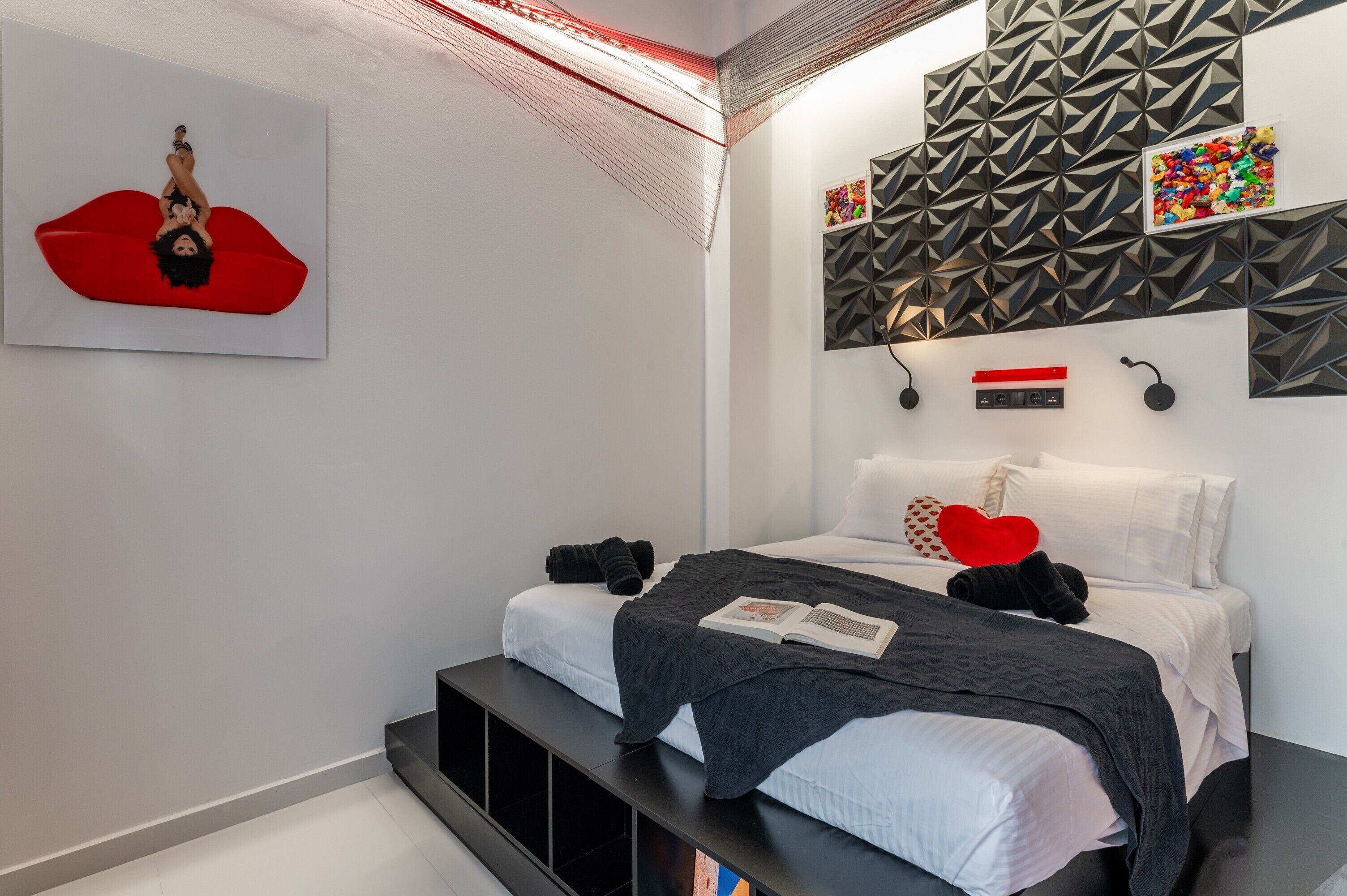 A modern bedroom with a bed, pillows, a book, and a wall art piece.