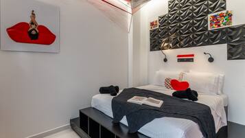 A modern bedroom with a bed, pillows, a book, and a wall art piece.