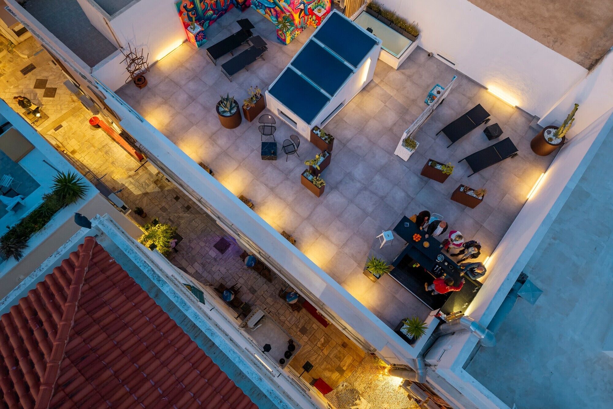An aerial view of a rooftop terrace with outdoor seating, planters, and a pool.