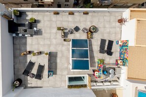 An aerial view of a rooftop with a swimming pool, lounge chairs, and potted plants. - Apartment 'Pop Loft Gallery' with Sea View, Wi-Fi and Air Conditioning (Ermoupoli)