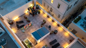 An aerial view of a courtyard with outdoor seating, a pool, and surrounding buildings. - Apartment 'Pop Loft Gallery' with Sea View, Wi-Fi and Air Conditioning (Ermoupoli)