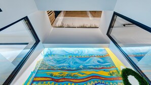 A modern interior with a glass railing, a skylight, and a colorful mural on the floor. - Apartment 'Pop Loft Gallery' with Sea View, Wi-Fi and Air Conditioning (Ermoupoli)