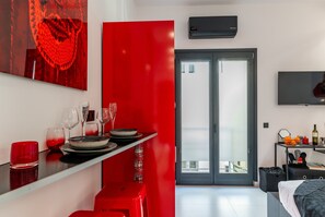 A modern room with a dining area, a TV, and a sliding door to the outside. - Apartment 'Pop Loft Gallery' with Sea View, Wi-Fi and Air Conditioning (Ermoupoli)