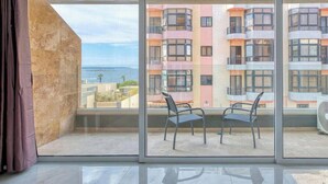 En rummelig balkon med udsigt over en farverig bygning og havet.