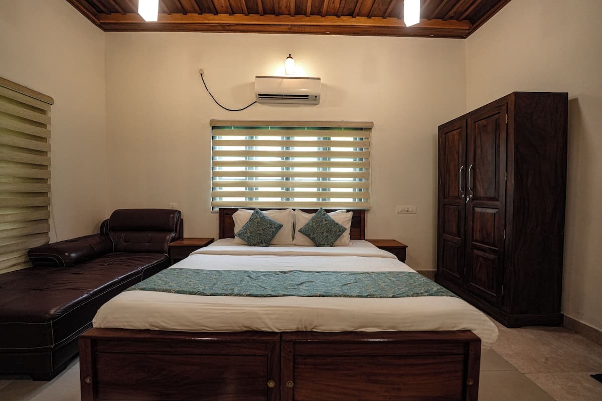 Een slaapkamer met een groot bed, een houten hoofdbord, een nachtkastje, een kledingkast en een raam met zonwering.