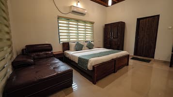 Une chambre à coucher avec un lit, une armoire en bois, un canapé en cuir et une fenêtre avec des stores.