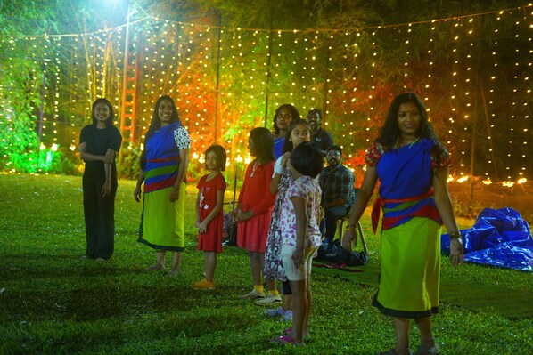 A group of people standing on grass under string lights. - Kings Flora Luxury Organic FarmResort (Kottathara)