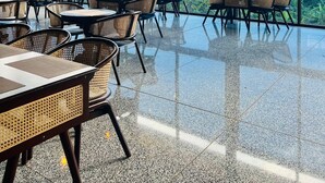 Ένας ευρύχωρος εξωτερικός χώρος για φαγητό, με μεγάλα παράθυρα που προσφέρουν θέα στα βουνά. Τραπέζια και καρέκλες είναι διατεταγμένα έτσι ώστε οι επισκέπτες να μπορούν να απολαύσουν τα γεύματά τους.