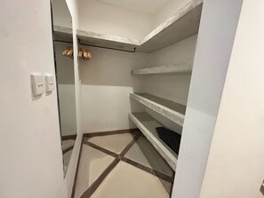 A small, empty walk-in closet with white walls, a tiled floor, and a single shelf with a black tray. - Spacious 7-bedroom villa in Canggu: Private chef, Pool, Movie theater (Badung)