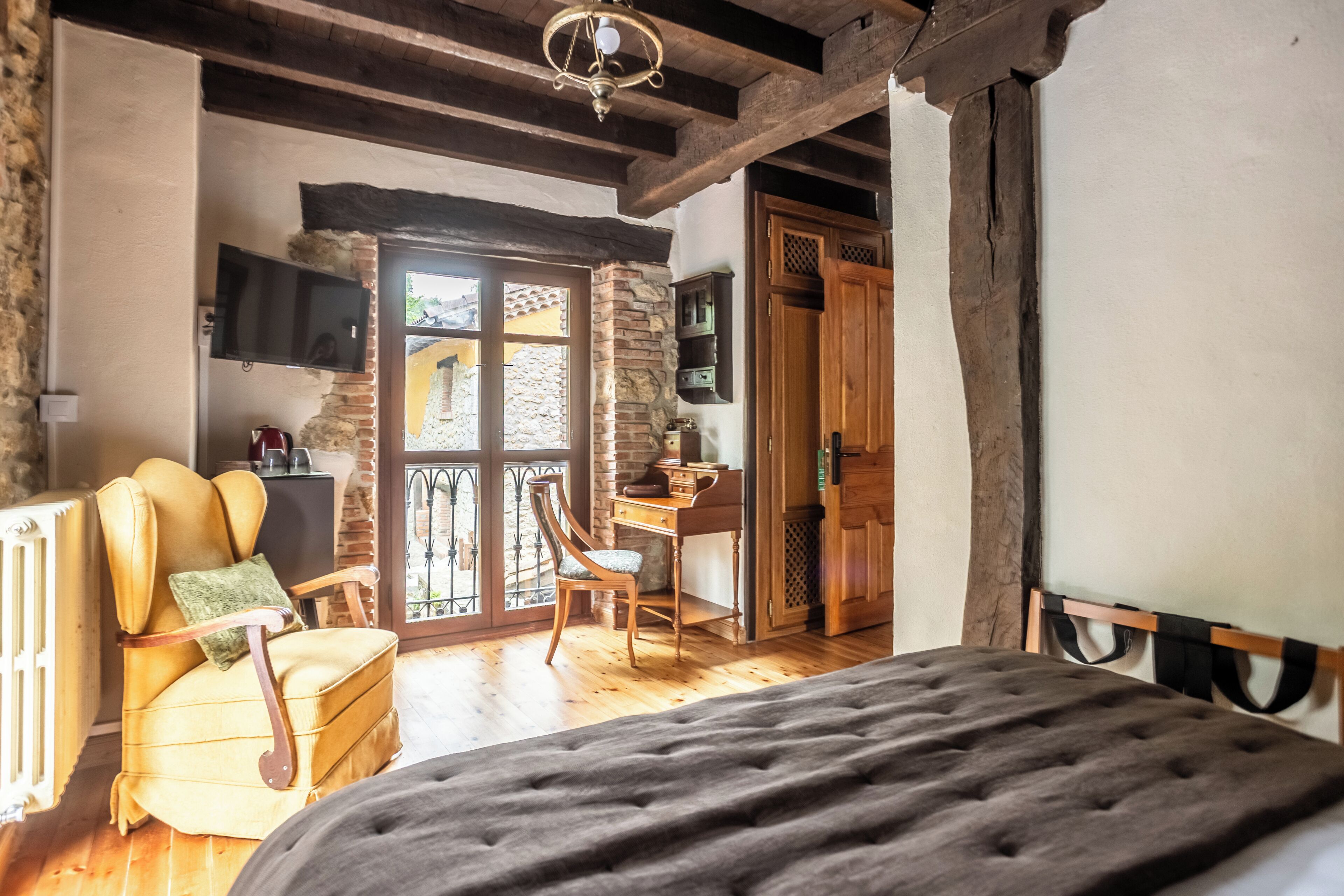 A bedroom with a bed, a chair, a desk, and a television.