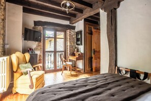 Un dormitorio con una cama, una silla, un escritorio y una televisión.